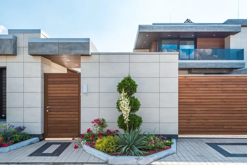 Modern huis met houten poort en een kleurrijke border langs het terras